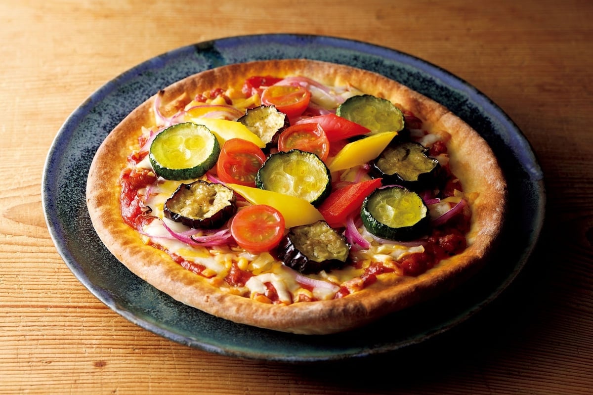 This is an image showcasing various food items and gifts. The Japanese cuisine dish, Suzunari's domestically sourced Hamo and raw wheat gluten and yuba shabu-shabu hotpot, is priced at ¥10,800 (tax included). The summer vegetable pizza and four-cheese pizza from La Bettola da Ochiai are available for ¥6,480 (tax included). For cost-effective options, Ibo Noshino Somen's premium quality somen noodles are offered at ¥2,376 (tax included), and Ninben's Honkatsuo Katsuobushi Story, 50 bags of 2g soft shaved bonito flakes, are priced at ¥2,214 (tax included). Additionally, there is a gift set of a Seibu/Sogo original insulated mini cooler bag available at ¥15,000 (tax included) from the Mid-Year Gift Center.