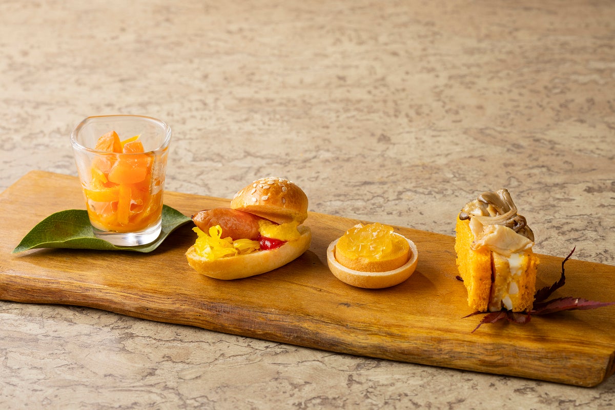 From left to right: Salmon and Butternut Squash Salad, Sausage and Curry-flavored Cabbage Hot Dog, Carrot Flan in a Monaka with consommé jelly, Roast Chicken and Egg Salad Sandwich with colorful vegetables and curry-flavored cabbage, and carrot flan in a monaka with consommé jelly.