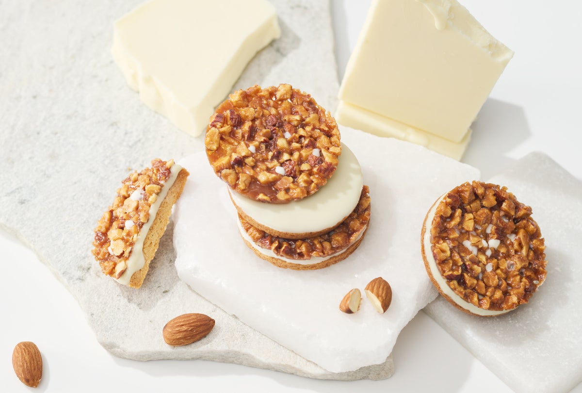 Caica has launched a new flavor of their popular innovative Florentan, called "Floranshocolat Sand <White>." It features a large, skin-on almond-topped tuile, layered with smooth white chocolate and a vanilla cookie with a subtle salty flavor. The combination highlights the rich taste of almonds, the gentle sweetness of white chocolate, and the vanilla flavor enhanced by the saltiness, offering a delightful textural experience. The new product is priced at ¥1,458 (tax included).” class=”wp-image-37939″>
<figcaption class=