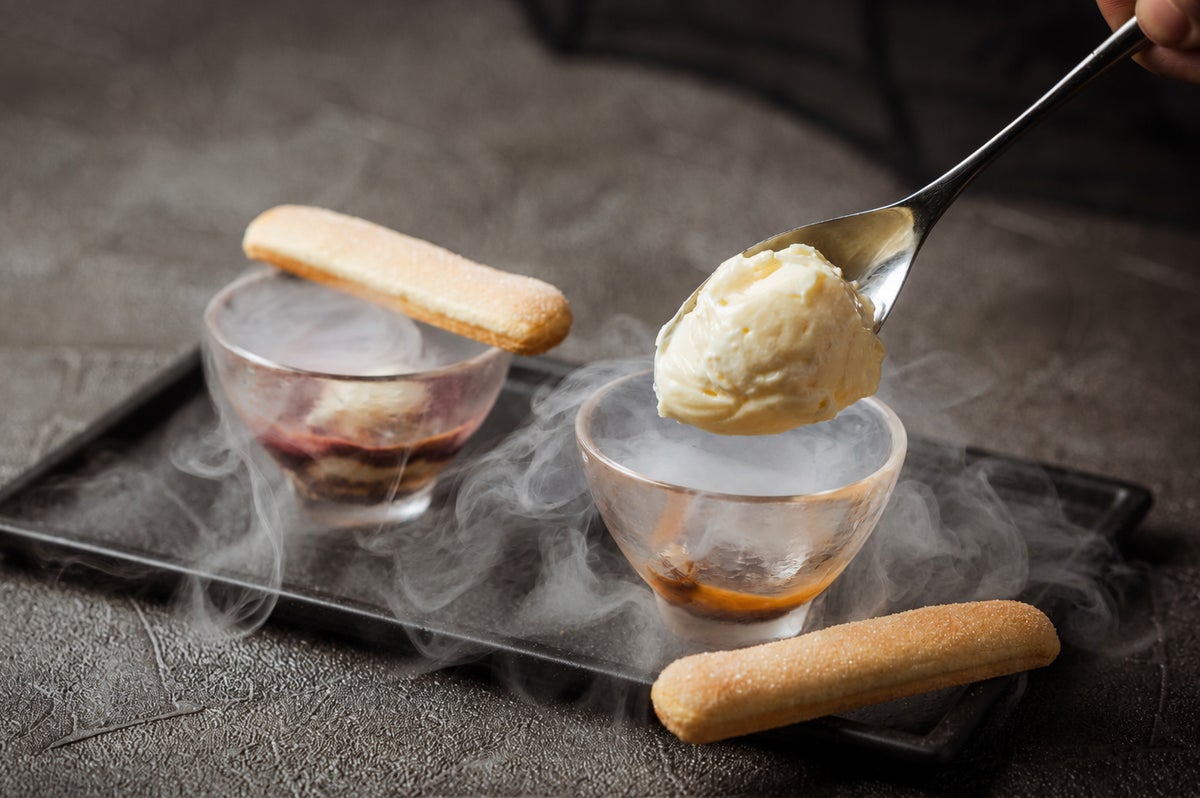 <Cold Tiramisu> Tiramisu layered with berry sauce and mascarpone cream on savoiardi, finished with espresso. Enjoy the live preparation using liquid nitrogen in front of you and the enchanting smoke effect.” class=”wp-image-41249″>
<figcaption class=