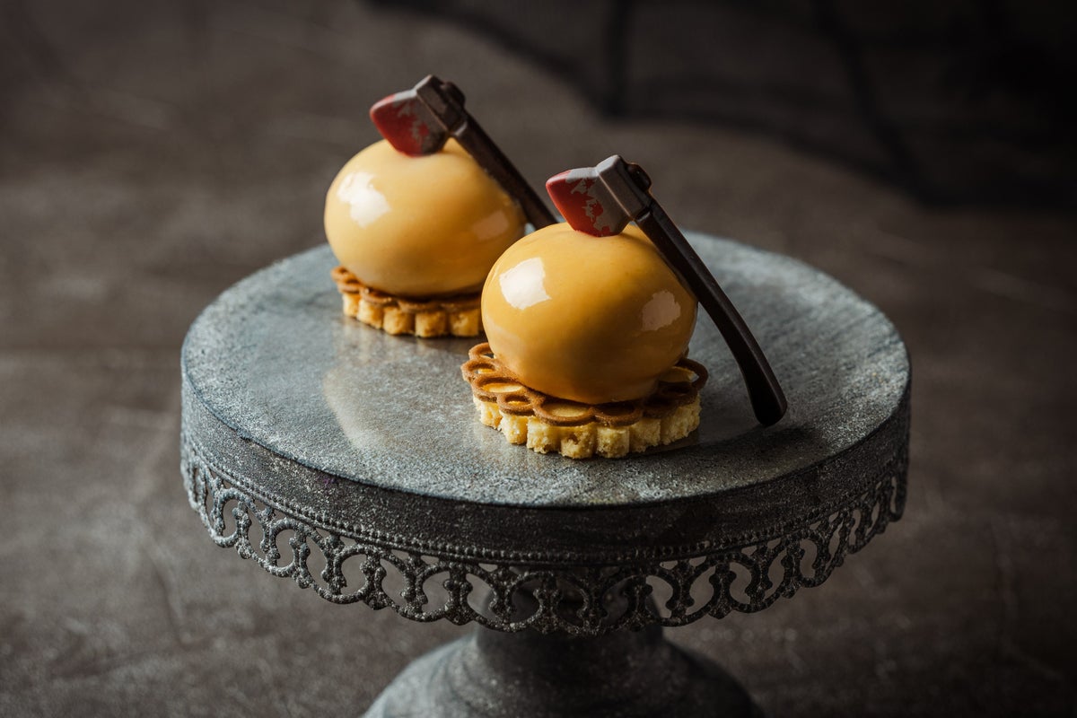 <Caramel Poire Mousse> Caramel mousse shaped into a sphere with pear jelly inside, finished with a glossy caramel glaze and topped with a chocolate shaped like an axe, creating a fun Halloween presentation.” class=”wp-image-41251″>
<figcaption class=