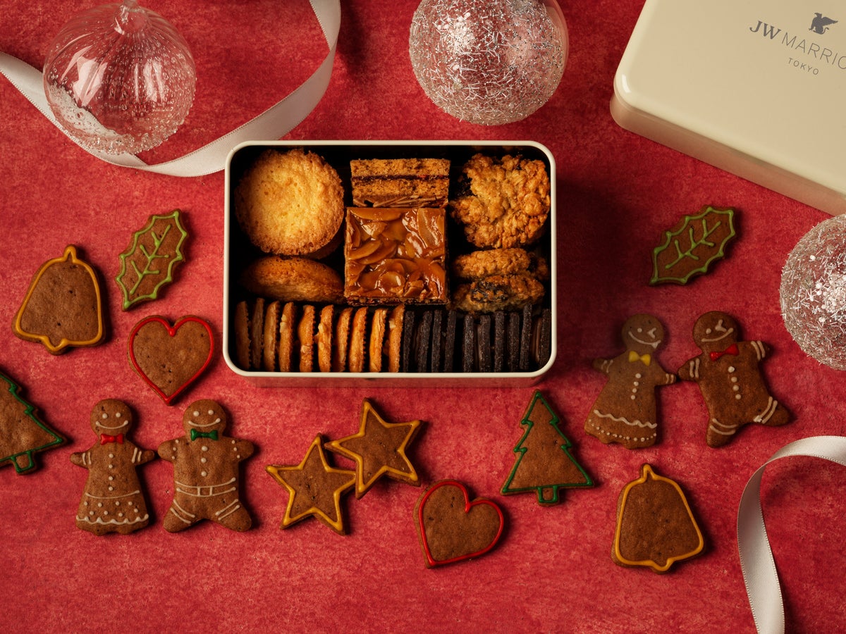 A festive cookie tin featuring six varieties: hand-painted gingerbread men, oatmeal raisin cookies, coconut galettes, florentines, almond sable, and chocolate sable. Perfect as a gift, these seasonal treats are exclusive to the holiday season.