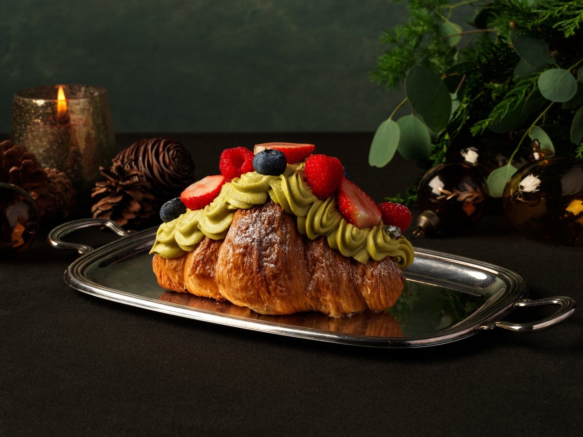 A festive croissant topped with pistachio custard, berry jelly, and decorated with pistachio chantilly, raspberries, and blueberries. This beautifully decorated Christmas-exclusive croissant combines rich flavors and vibrant colors for a joyful holiday treat.