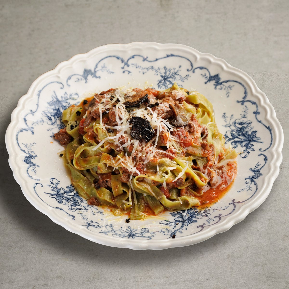 Truffle-scented Beef and Black Cabbage Bolognese. We slow-cooked domestic coarsely ground beef and black cabbage, which becomes more flavorful the longer it simmers, to create our homemade Bolognese sauce. Finished with a hint of truffle, this dish offers a rich depth of flavor and satisfying texture. The pasta used is homemade tagliatelle made with spinach, with its wide noodles perfectly coated in the rich Bolognese sauce, and the vibrant green color adds a lively touch to the presentation.