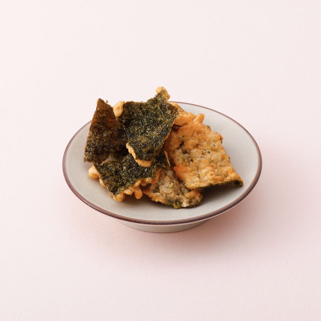 The new product lineup includes the Thick Cut Menta Cheese Potato Chips for ¥378 (tax included), along with the popular Menta Mayo Ika Tempura for ¥486 (tax included). Last year's hit, the Nuri Pan Menta Toast, is also available for ¥432 (tax included), as well as the spicy Menta Takana rice seasoning for ¥432 (tax included). Other offerings include Menta Takana for ¥432 (tax included), Menta Dashi Chazuke for ¥432 (tax included), and Rich Menta Cream Risotto for ¥410 (tax included). Additionally, the crispy Nori Tempura with Menta Garlic flavor is priced at ¥324 (tax included). To commemorate this collaboration, the Harajuku main store is offering freshly made Menta Cut Glass (Silk Box) 150g for ¥1,836 (tax included).