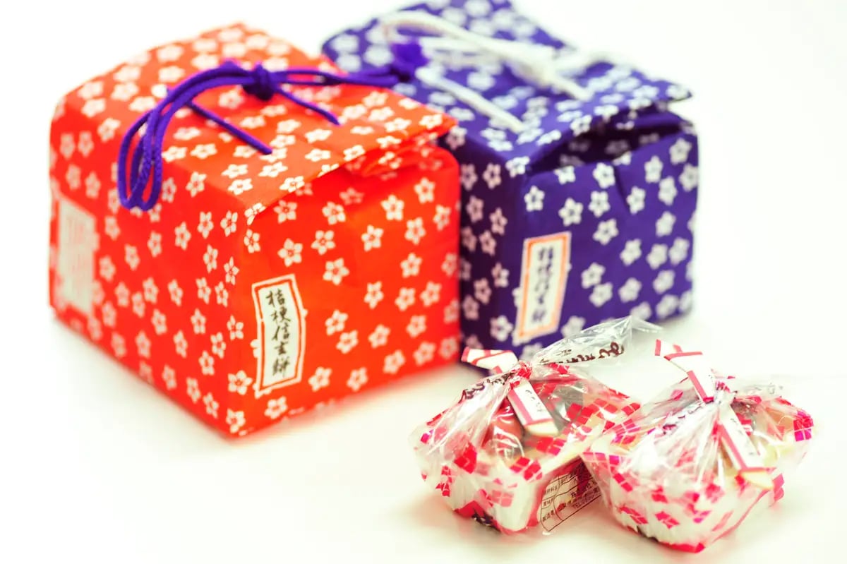 Kikkōya's signature product is wrapped in a furoshiki with the Takeda-bishi pattern, featuring handmade mochi coated with fragrant kinako and generously drizzled with black honey, embodying the local taste of Yamanashi Prefecture.